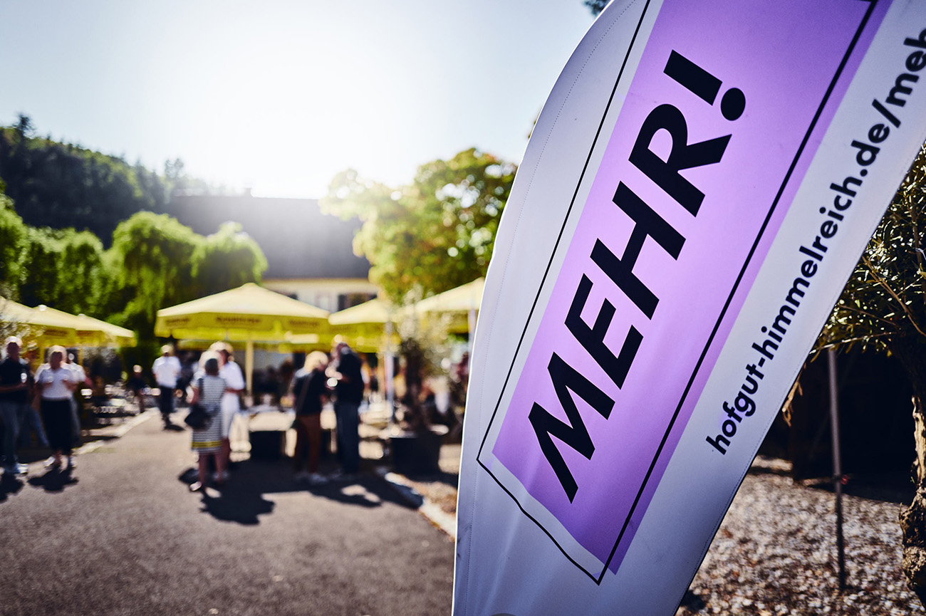 Beachflag der Fundraising-Kampagne „Gemeinsam MEHR.“ vor dem Hofgut Himmelreich bei einer Open-House-Veranstaltung.
