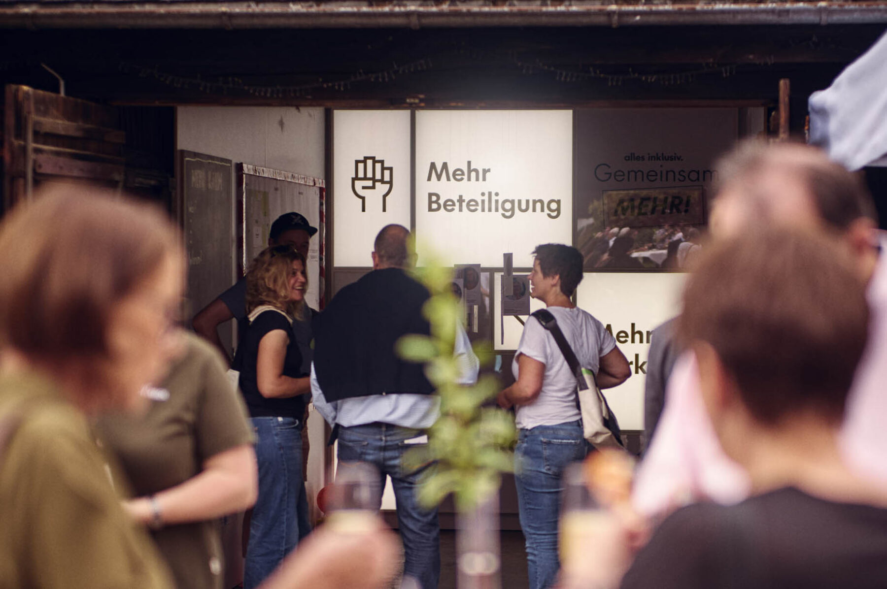 Besucherinnen und Besucher im Showroom der Fundraising-Kampagne „Gemeinsam MEHR.“ beim Open House im Hofgut Himmelreich.