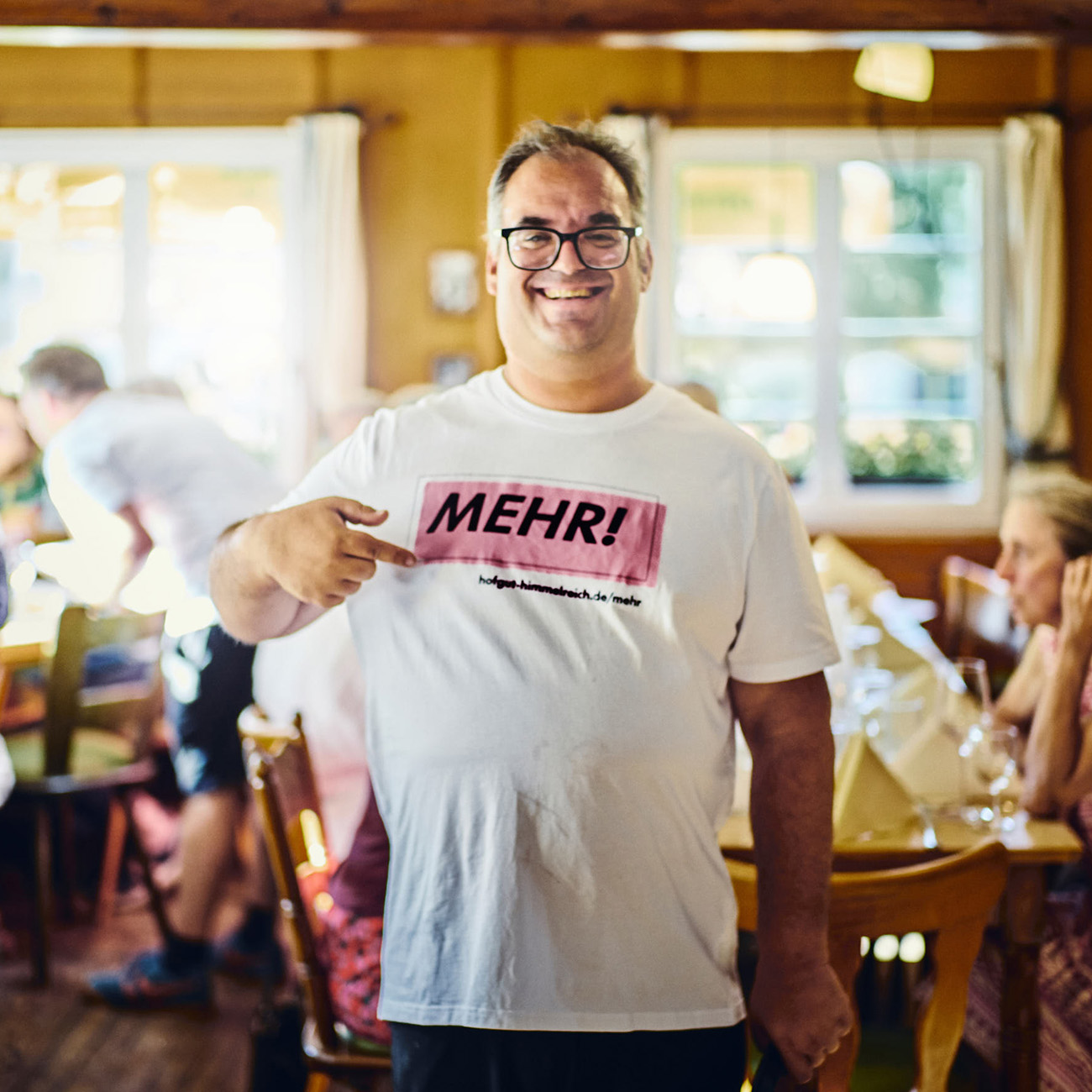 Mitarbeiter des Hofgut Himmelreich trägt das Kampagnenmotiv „Gemeinsam MEHR.“ und zeigt auf das T-Shirt.